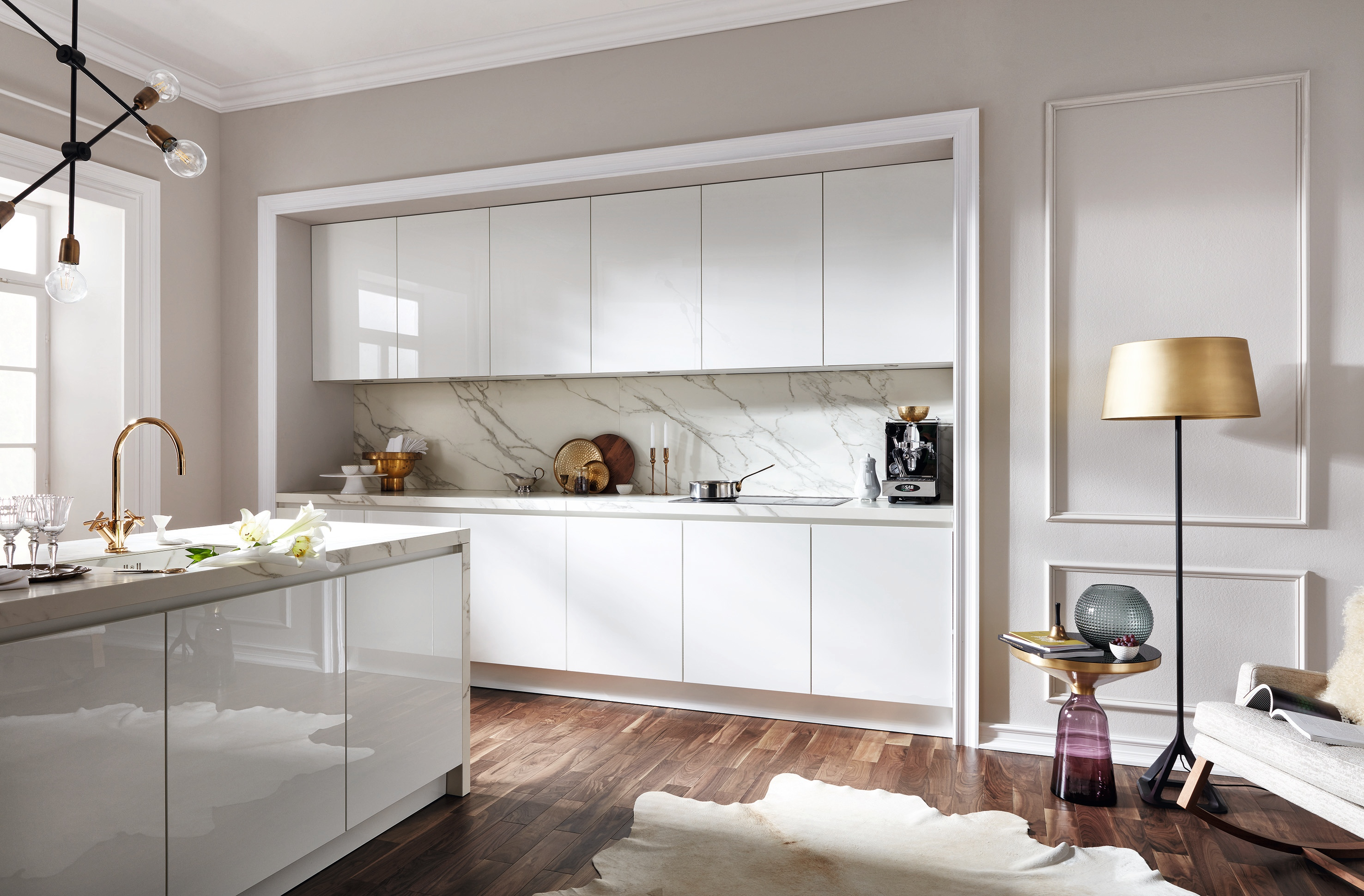 Eingekofferte weiße Küchenzeile mit einer seitlich stehenden Kücheninsel. Rückwand und Arbeitsplatte aus heller Keramik