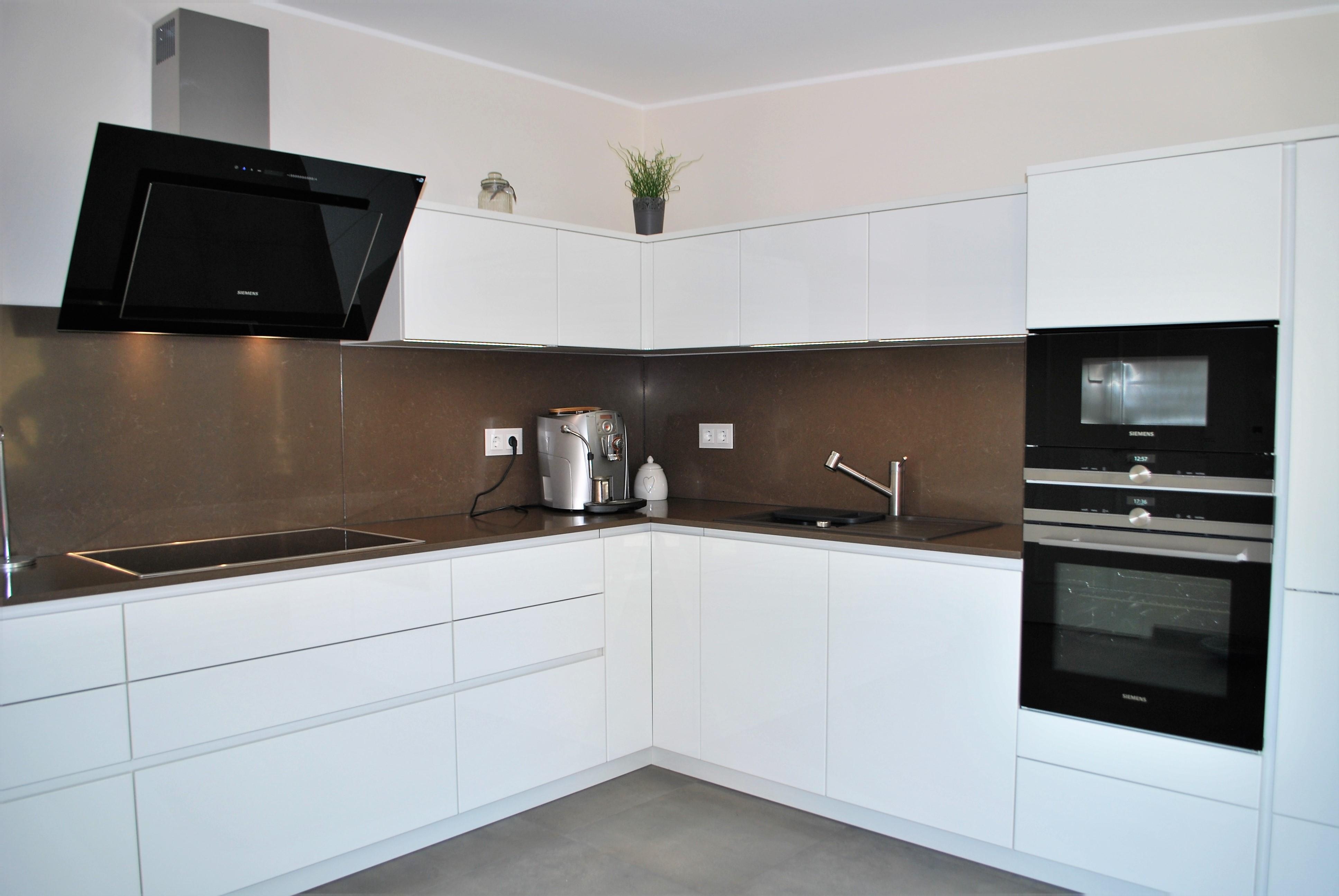 Weiße L-Küche mit dunkler Arbeitsplatte und Nischenverkleidung