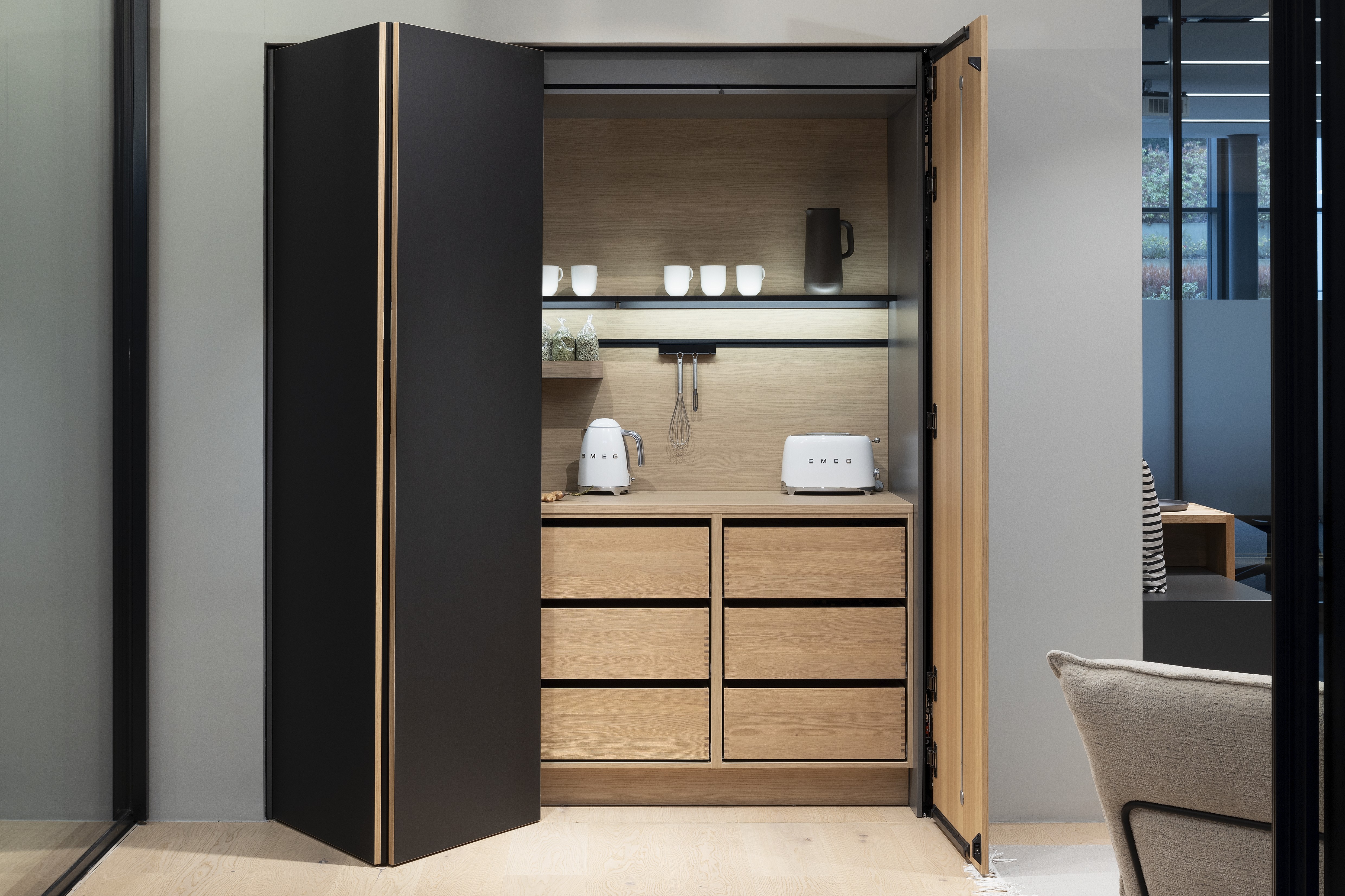 APL: Feineiche-natur Repro 25 mm Front: AV 7080 Schwarz Linoleum Korpus: Designkorpus Feineiche-natur Repro Griff: PTO Kehlleiste Graphit gebürstet Geräte: SMEG  Features: Linoleum Front, Ordnungssystem Boxen, Teeküche, Einschubtüren (Pocket Door System von Häcker) + Unterschrankregale mit Massivholzauszügen