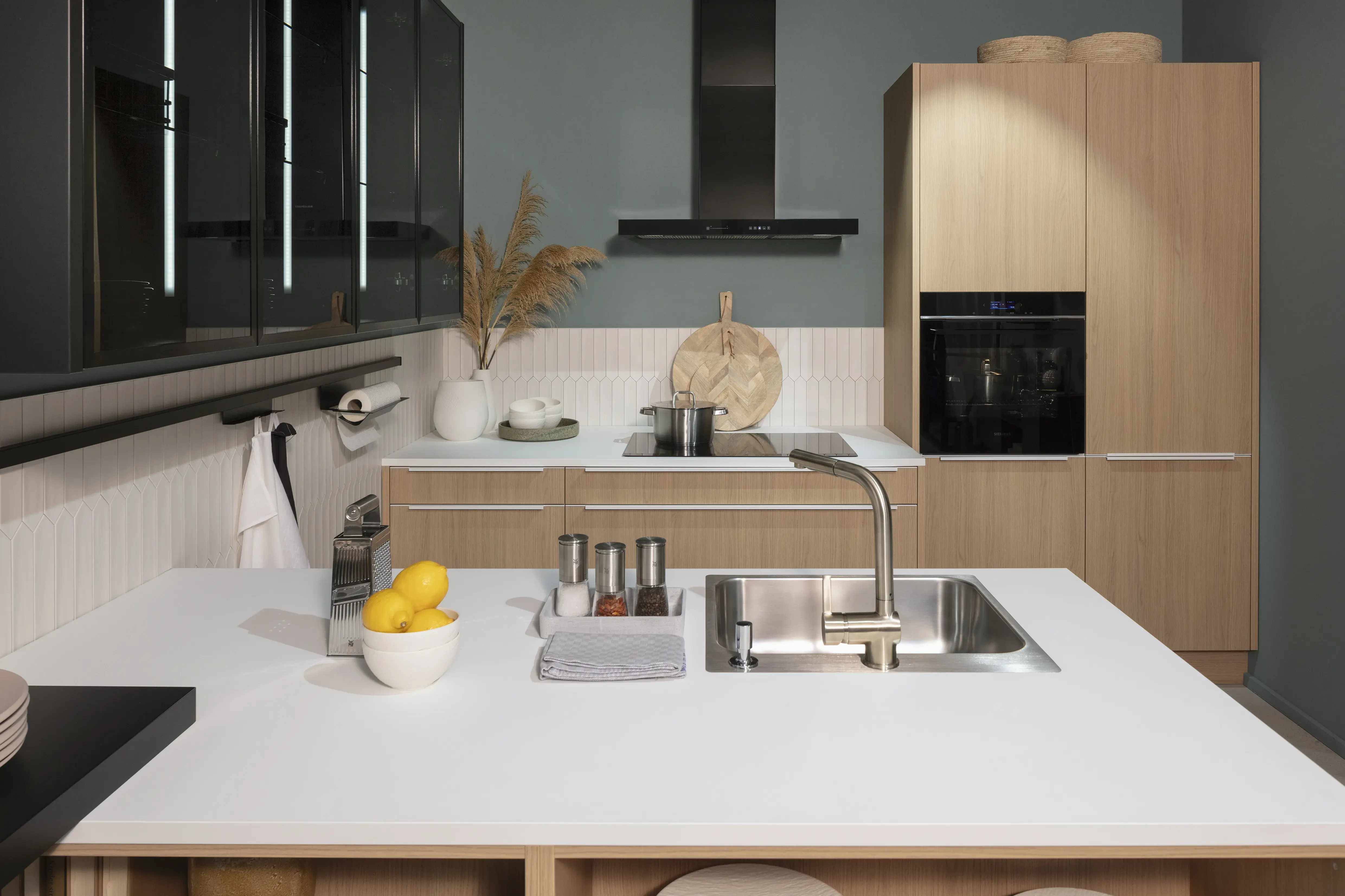 Arbeitsplatte mit Spüle und Küchenzeile mit Kochfeld, Backofen und Dunstabzugshaube. 